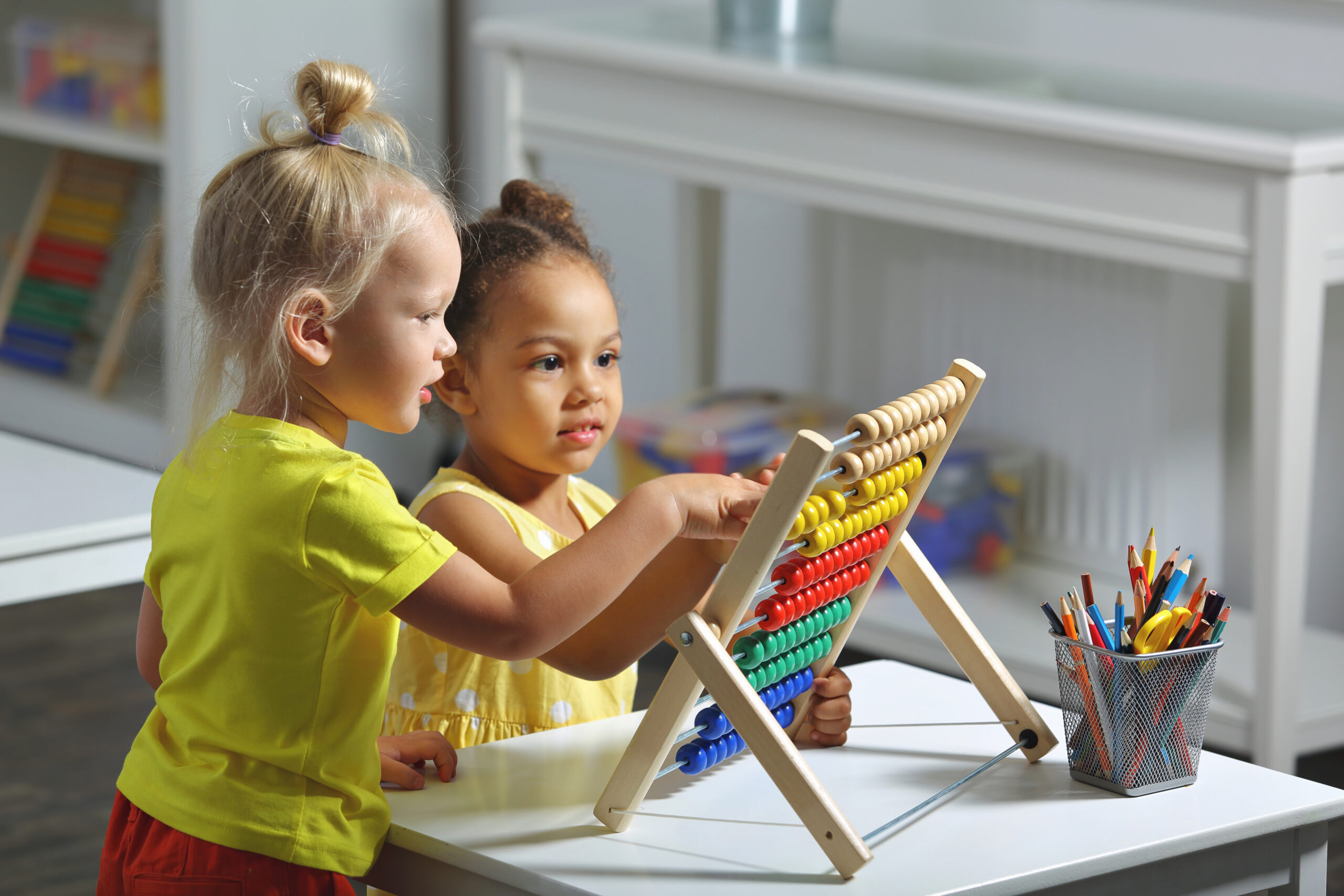 children of different races sit together at the table and count on the abacus