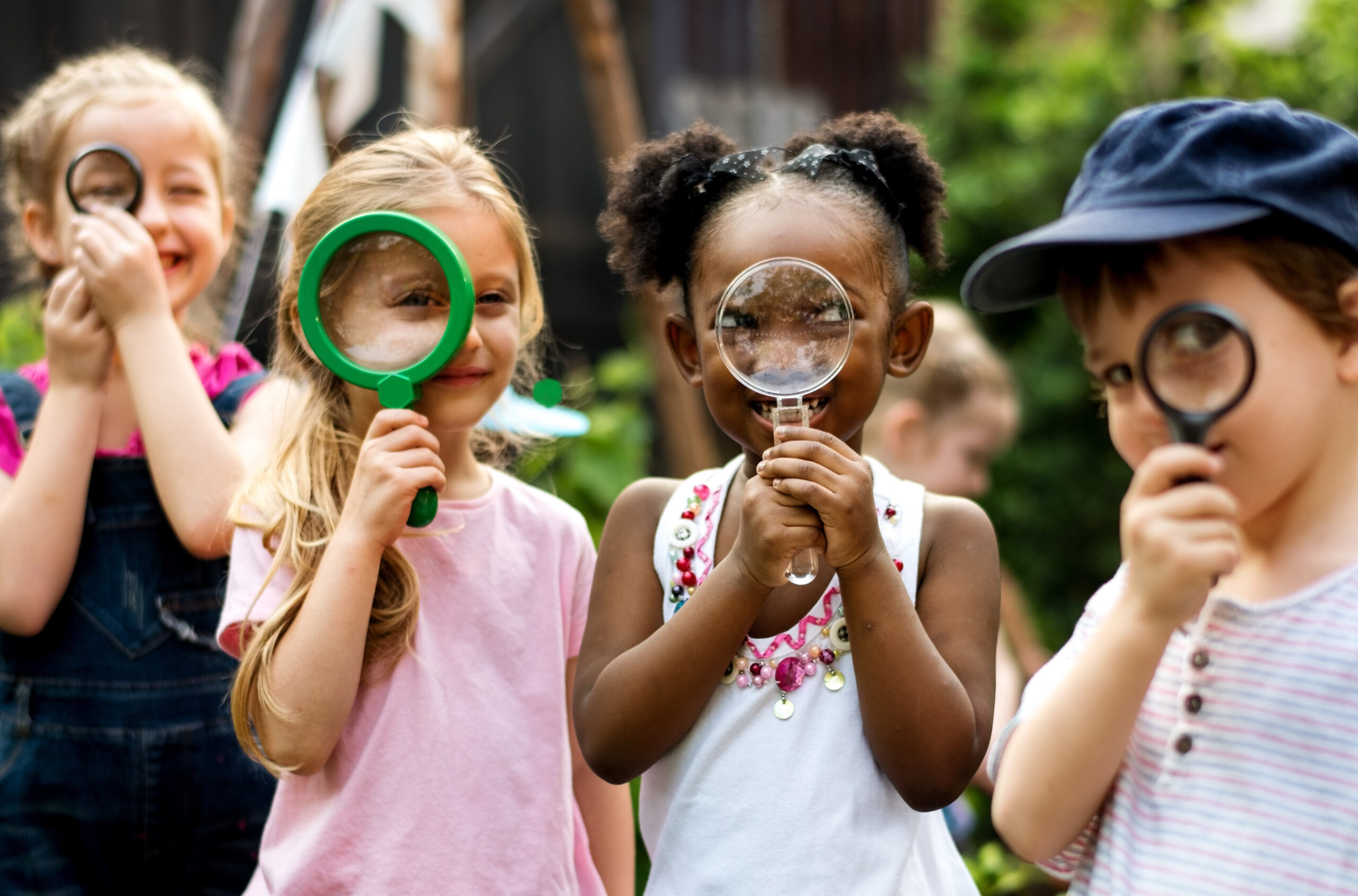 Group of kindergarten kids friends holding magnifying glass for